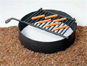 Fire Ring with Flip-back Grate, black rust-resistant firebox with attached cooking grate and cool-coil handle in outdoor setting