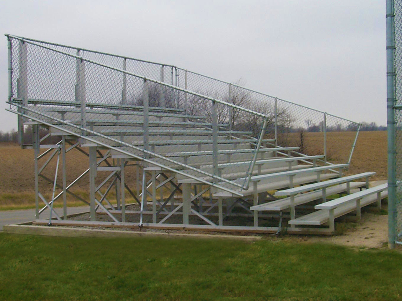 10 Row Preferred Bleachers aluminum seating with chain-link guardrail on grassy field, non-elevated design with anodized seats and foot planks