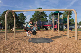Children playing on a durable arch-frame playground swing set with a rotationally-molded tire swing in vibrant colors