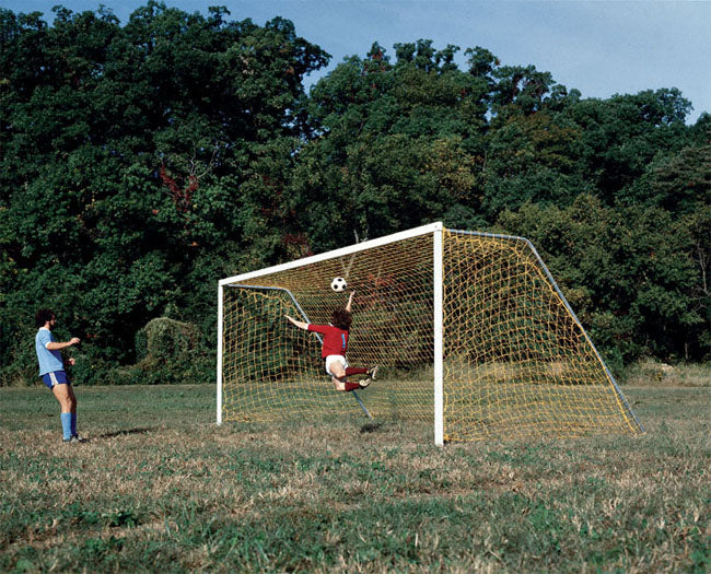Official Steel Soccer Goals, Set of 2 with yellow nets on grassy field, goalkeeper diving to block soccer ball