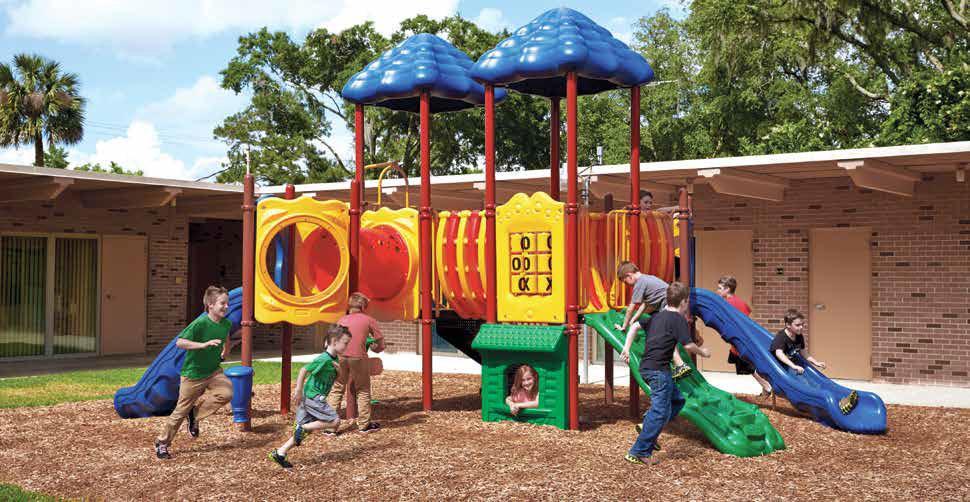 Colorful outdoor playground with two blue roofs, twisting slides, climbing elements, and children playing on wood chips