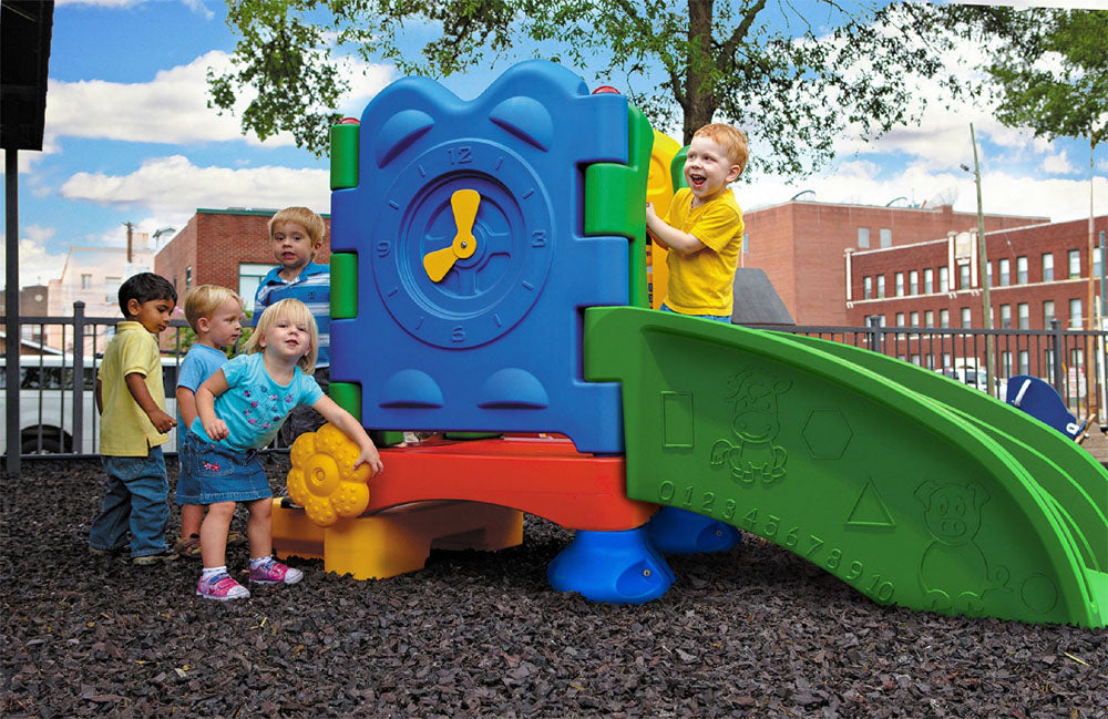 Colorful toddler playground with interactive clock, slide, ramp featuring animal, shape, ABC, and number designs outdoors