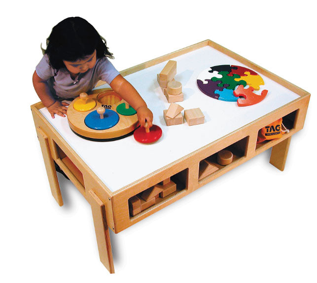 Child playing at hardwood activity table with raised edges, storage cubbies, and colorful wooden toys on white surface