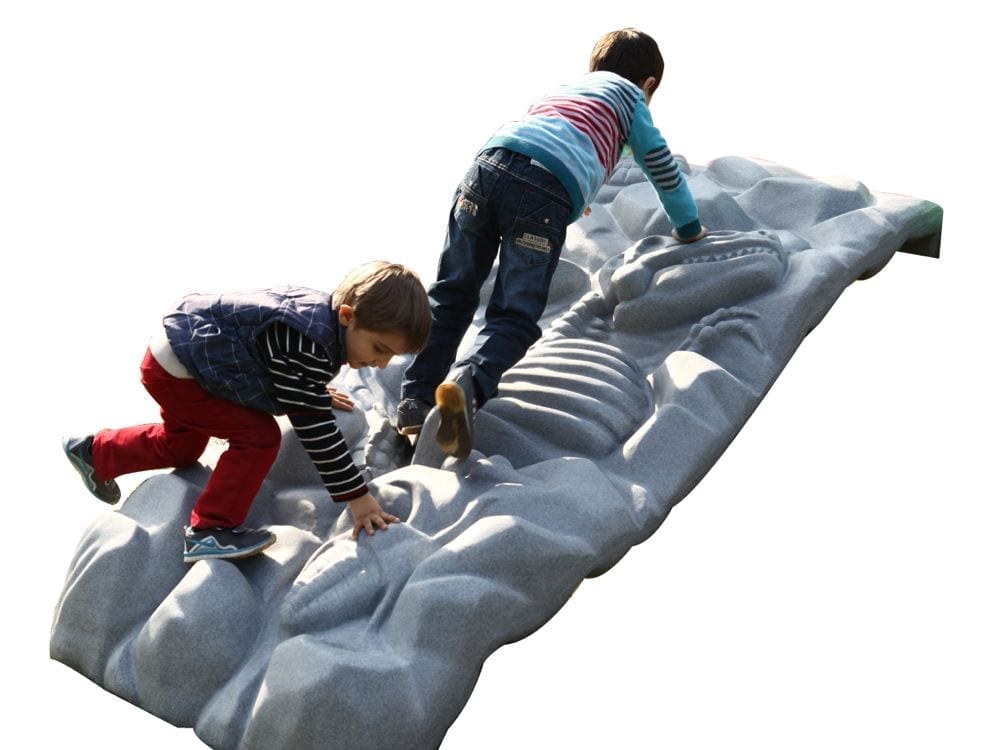 Two boys climbing a large gray dinosaur fossil-themed playground climber with textured bones and rock details