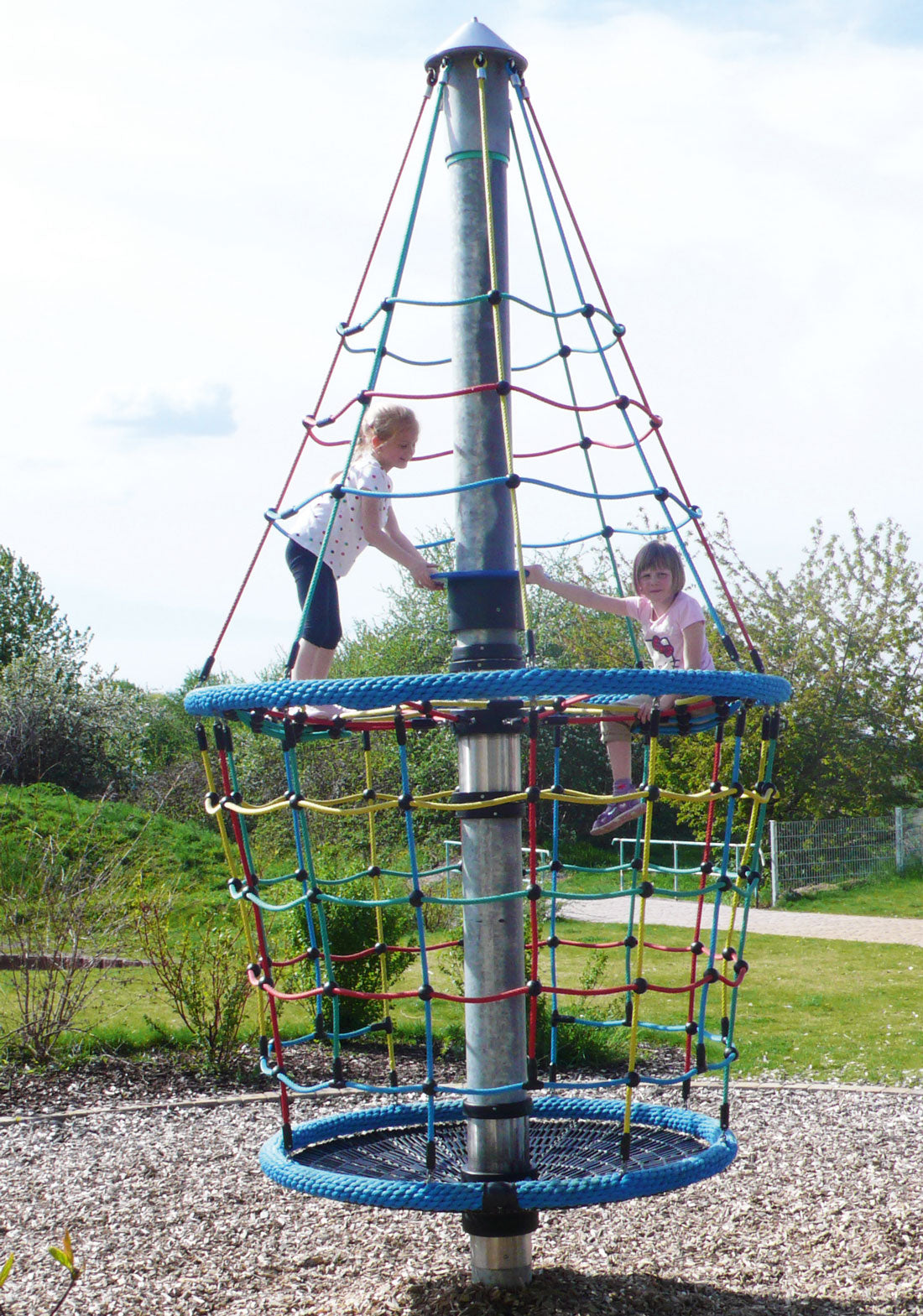 Vertical climbing and spinning play structure with colorful rope netting and two children playing outdoors