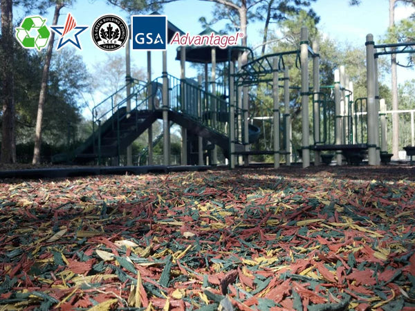 Playground surface with multicolored loose fill rubber mulch made from recycled tire buffing beneath playground equipment