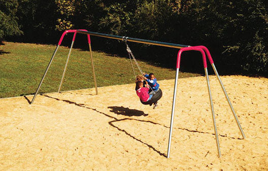 Two children swinging on a heavy-duty tire swing with galvanized steel tripod frame over sand playground surface