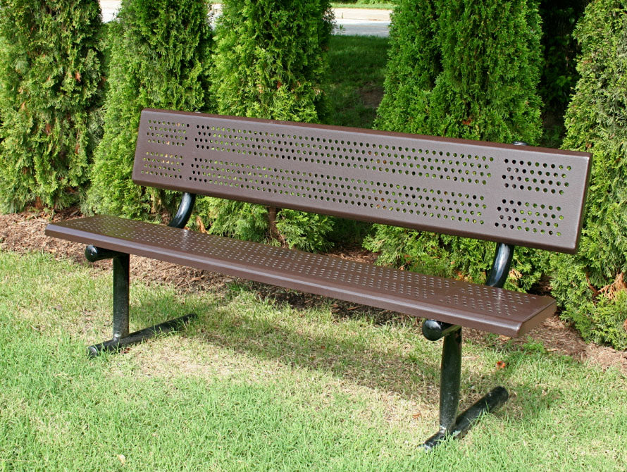 Brown perforated steel park bench with backrest, black metal legs, set on grass near green shrubs