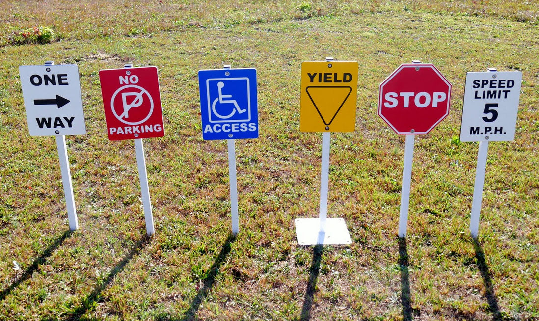 Traffic Signs For Trike Path on grass featuring one way, no parking, handicap access, yield, stop, and speed limit signs for children's outdoor safety play.