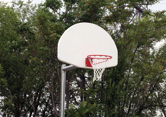 Adjustable Fiberglass Fan Basketball Goal with white backboard, red rim, and steel post set outdoors among green trees