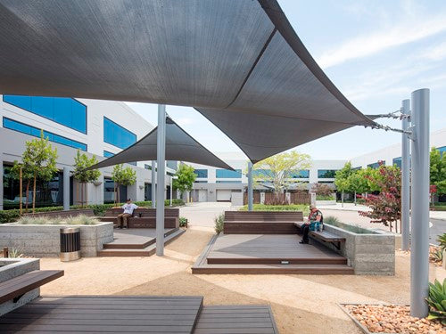 Four-point hypar sail shade with hyperbolic fabric stretched between tall metal columns over outdoor seating area