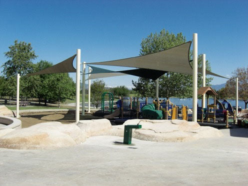 Triangular 3-point sail shade with varying column heights providing shade over playground equipment.