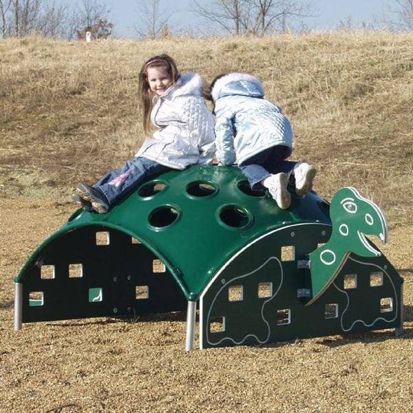 Green turtle-shaped outdoor climbing structure with circular holes and square cutouts, two children playing on top