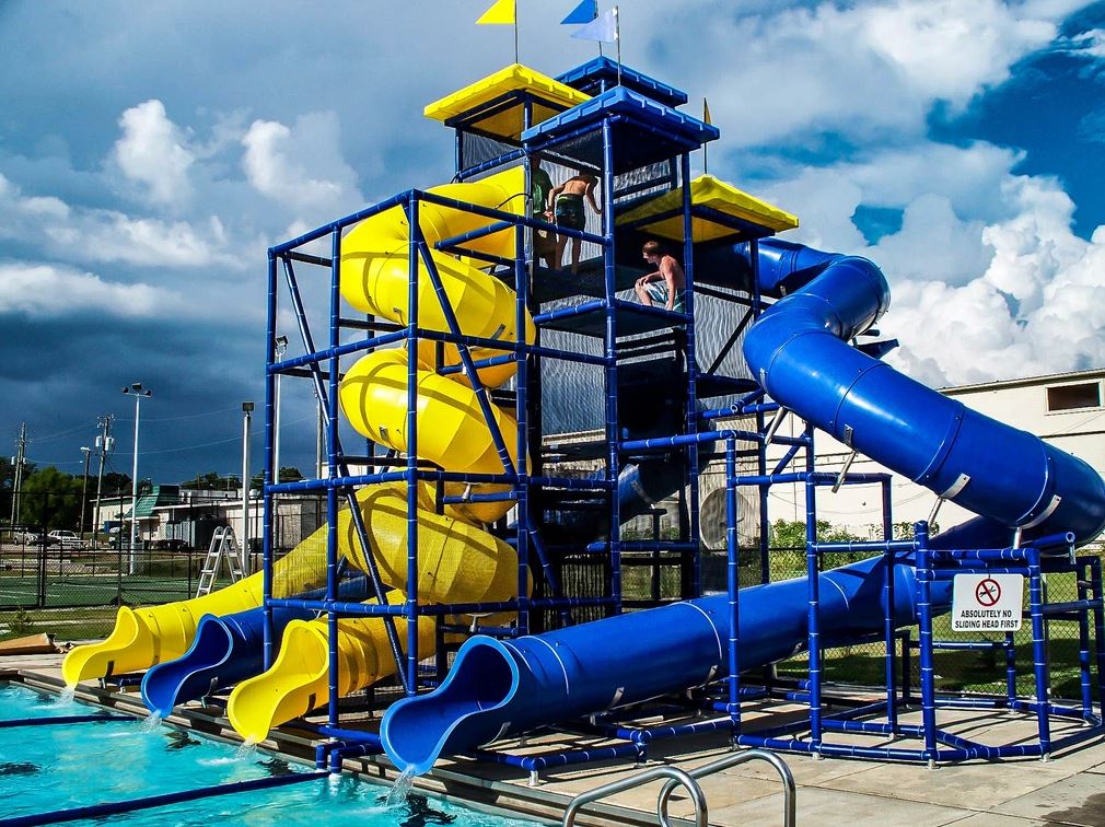 Multi-level poolside water slide structure with four colorful slides, including spiral and curved flumes, vibrant and thrilling design