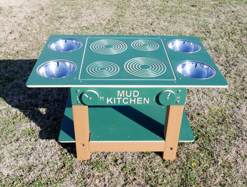 Island Mud Kitchen Commercial Play Event with green tabletop, four metal bowls, stove burner designs, and turning knobs on outdoor grass