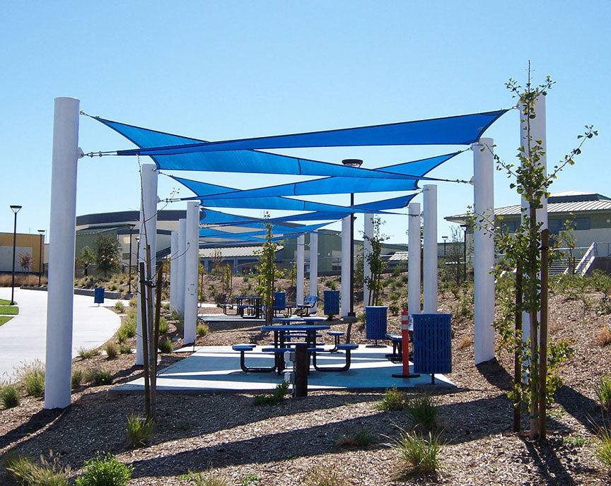 Sail Shade Structure Custom with blue hyperbolic fabric sails stretched over white columns shading picnic tables in a landscaped park
