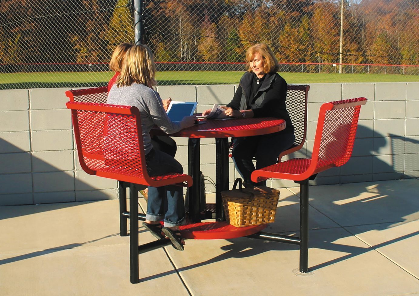 Ultra Bar Height Table with attached red chairs, diamond-patterned round top, outdoor setting with three seated people