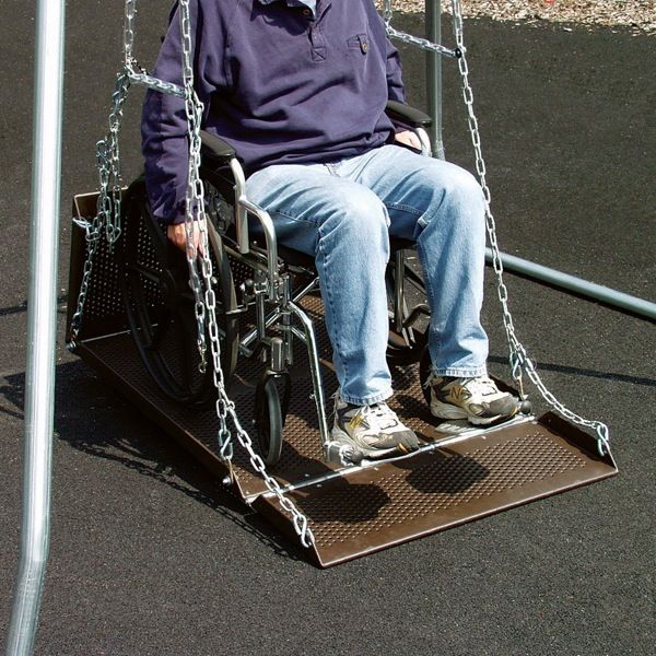 Wheelchair user on brown metal ADA accessible swing platform with safety chains on playground surface