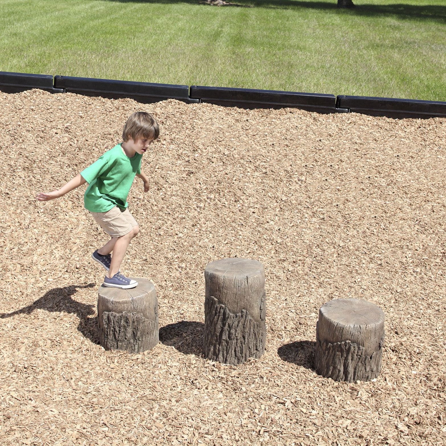 A child stepping on nature-themed tree stump steppers in a playground setting.