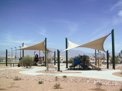 Beige four-point hypar sail shade with hyperbolic fabric stretched over tall green columns above playground equipment