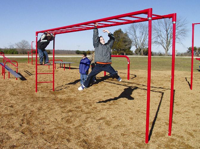 Red inclined climbing ladder with children playing and hanging, outdoor fitness and playground equipment.