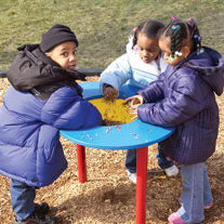 Single Bowl Sand And Water Table with three children playing outdoors on wood chip ground, colorful blue and red table encouraging sensory exploration