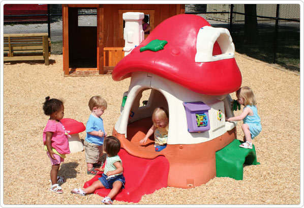 Colorful mushroom-shaped toddler playhouse with interactive panels, slide, small steps, and children playing around it