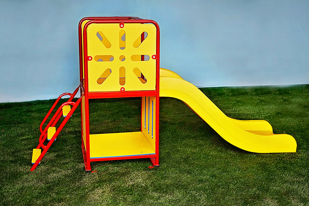 Compact playground slide with red frame, yellow sunburst panels, steps, and high-sided slide on green turf