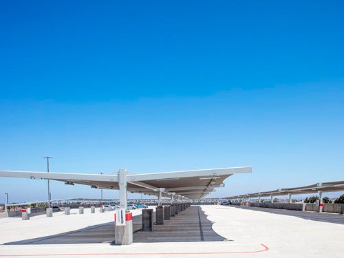 Modern cantilever double slanted fabric shade canopy with two supporting columns over parking area under clear sky
