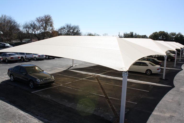 Rectangular hip roof shade structure with four white posts covering parking spaces, providing UV protection and cooling.