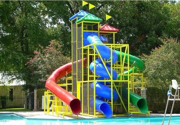 The Atlantic Ocean Water Slide with red, blue spiral, and green curved tube slides by a pool with yellow framework and flags