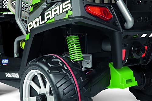Close-up of green suspension and large black tire with red traction band on a children's off-road ride-on vehicle wheel and shock absorber.