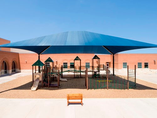 Large blue rectangular hip roof shade structure with four posts covering playground slides and climbing equipment
