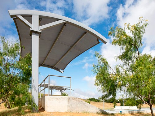Panorama Cantilever Shade Structure with elegantly arched roof shading playground area under clear blue sky
