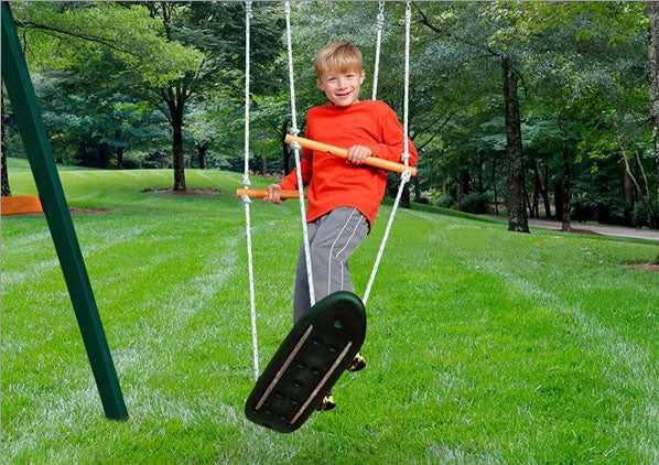 Child in red shirt on Skateboard Swing with molded plastic seat and rope, green backyard playset setting