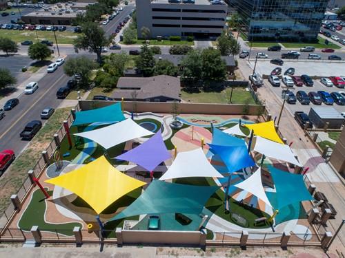 Overhead view of colorful 4-point hypar sail shade structures with hyperbolic fabric shapes over playground area