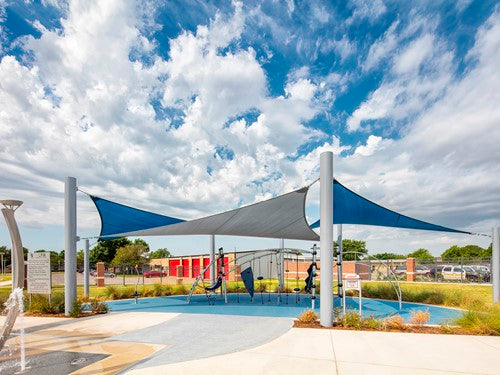 Four-point hypar sail shade with blue and gray fabric stretched over tall columns creating a hyperbolic outdoor shaded area