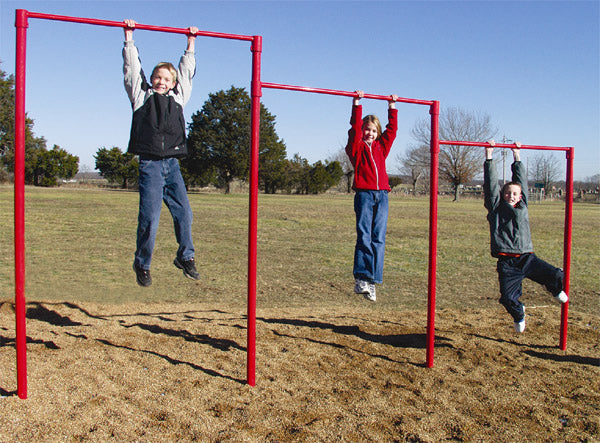 Three children hanging from red horizontal bars on outdoor fitness climbing equipment in a grassy park setting