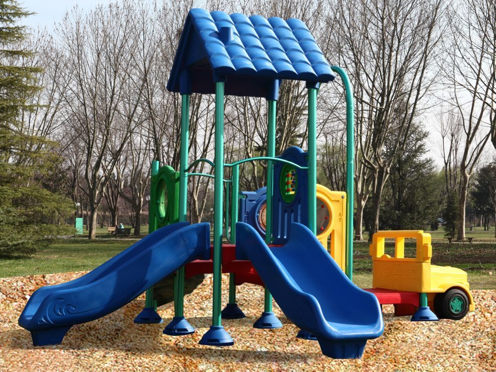 Christopher Columbus Explorer Center Early Childhood Playground with blue slides, yellow play truck, green support poles, outdoor park setting