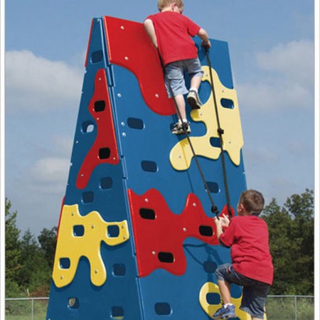 Multi-color outdoor climbing wall with abstract cutouts, assistance ropes, and two children climbing actively