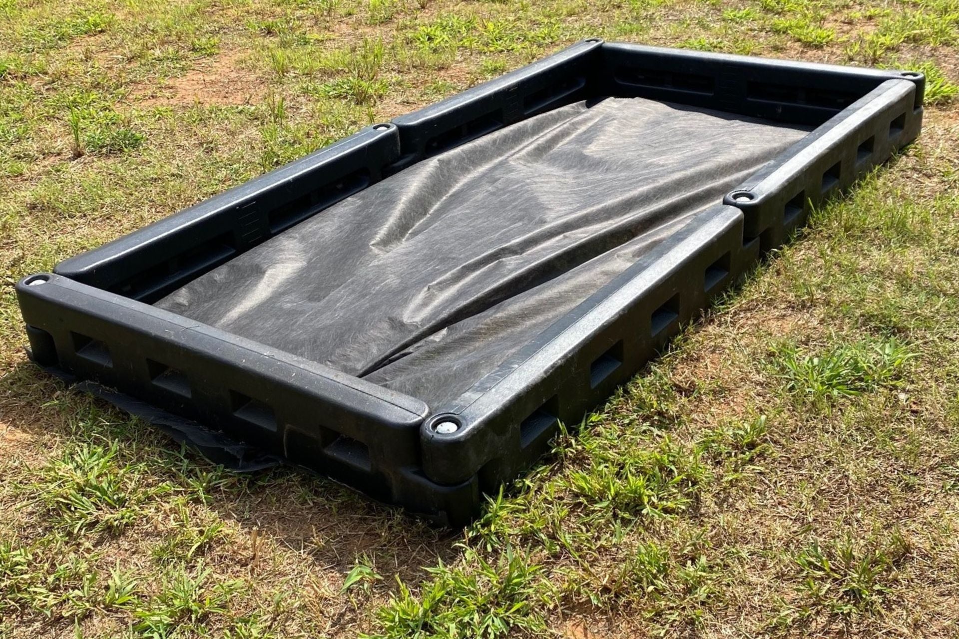 Black plastic interlocking playground border with spike, placed on grass with black liner inside, durable and lightweight design