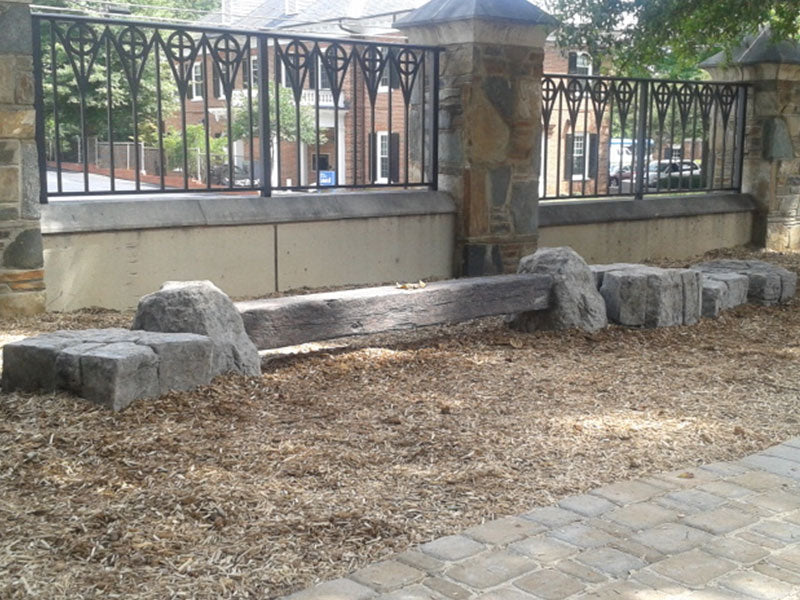 Rock Balance Beam with nature-inspired rock ends and composite railroad tie on outdoor mulch near stone pillars