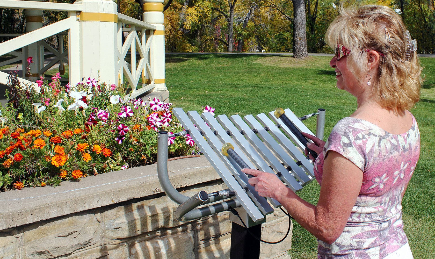 Aria Outdoor Musical Park Instrument with nine aluminum keys and mallets in a sunny garden near colorful flowers