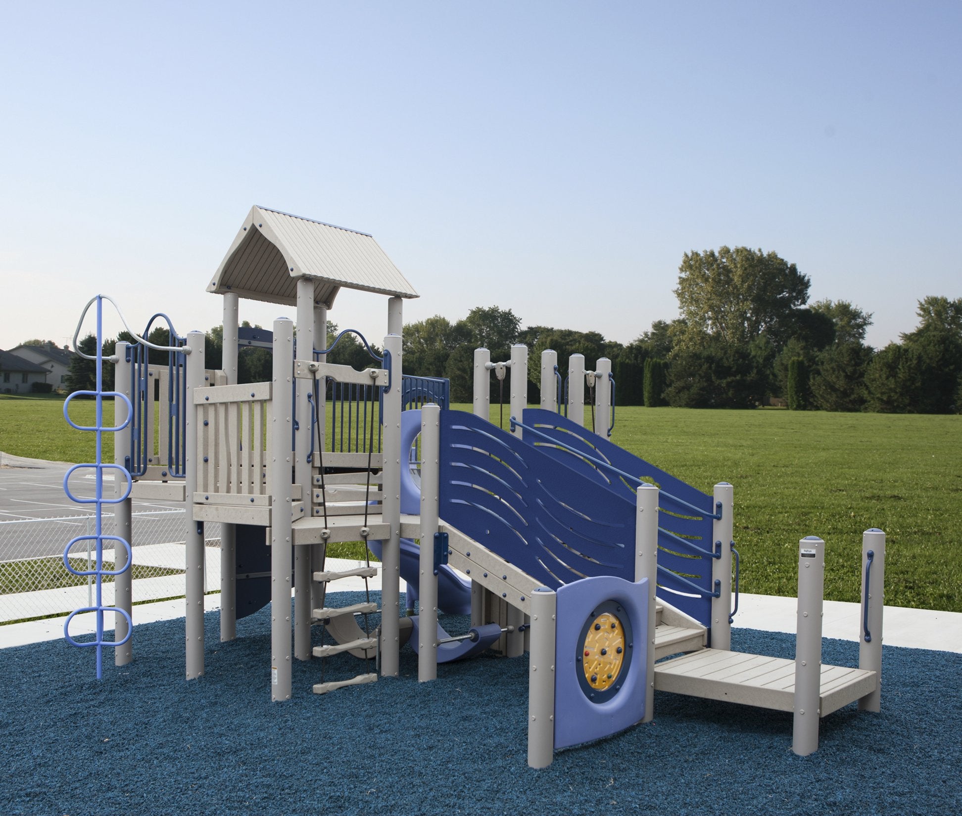 Compact playground structure with blue and gray climbing panels, rope ladder, spiral slide, and shaded platform on blue safety surfacing