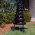 Outdoor colorful bell tree percussion instrument with seven rainbow-colored bells on a black metal frame and two mallets.
