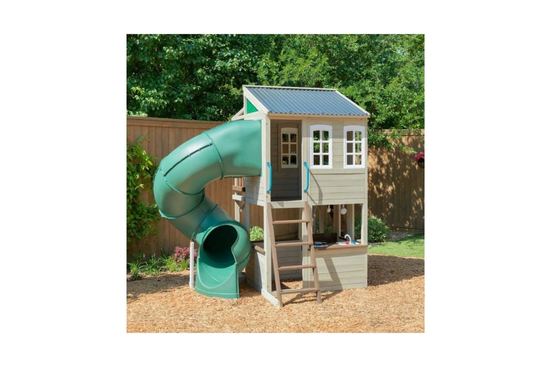 KidKraft Cozy Escape Playhouse wooden two-story backyard playhouse with green twisty slide, ladder, windows, and front porch bench
