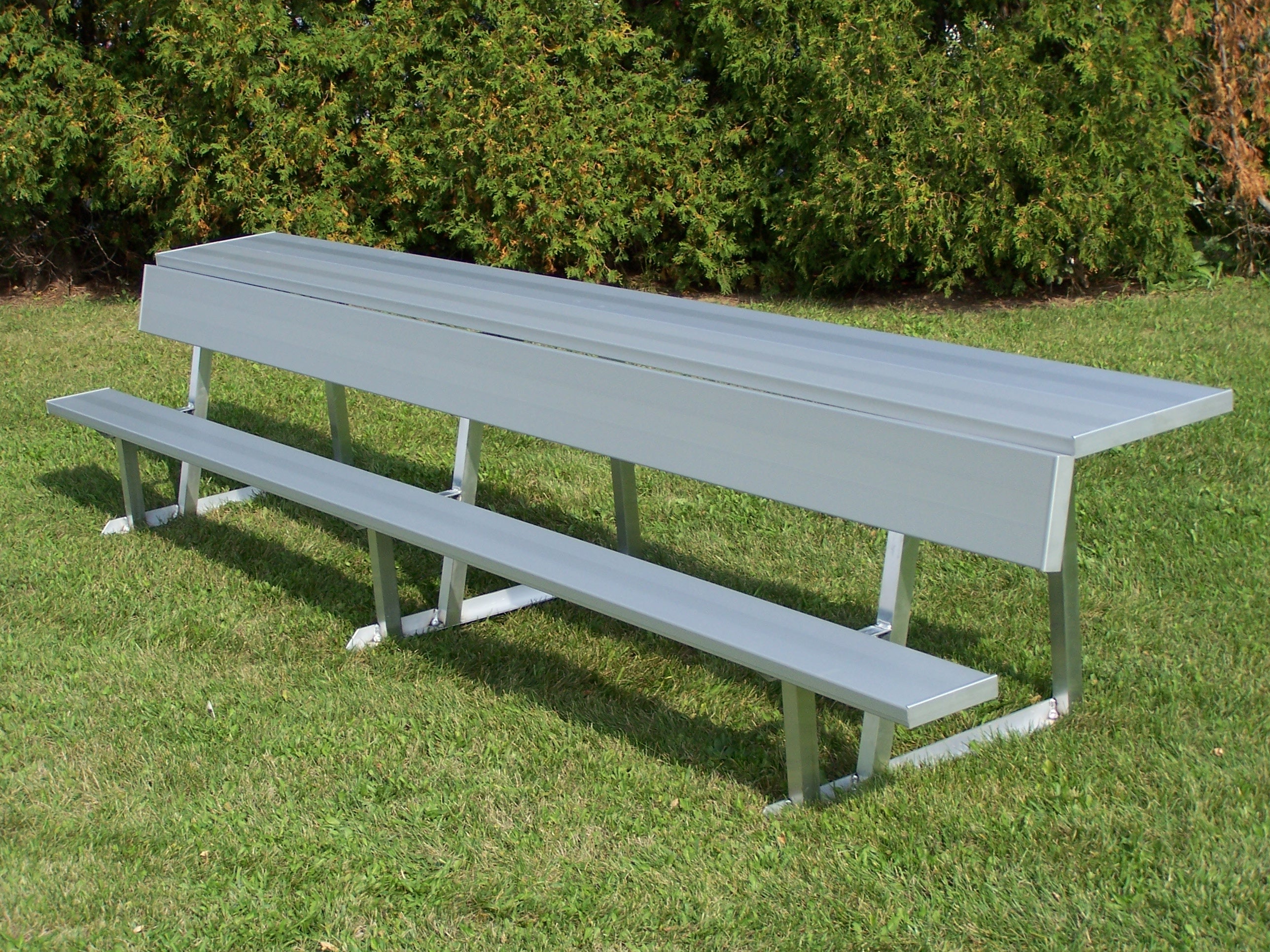 Portable Bench with Backrest & Shelf in anodized aluminum with sturdy legs on grass near green shrubs