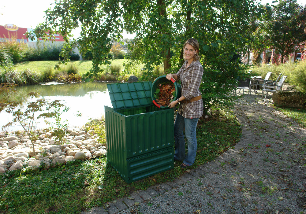 Eco King 600 Compost Bin in green with open lid, woman adding organic waste in outdoor garden setting