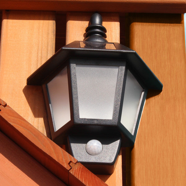 Black solar lantern with frosted panels mounted on cedar wood frame of outdoor wooden swing set