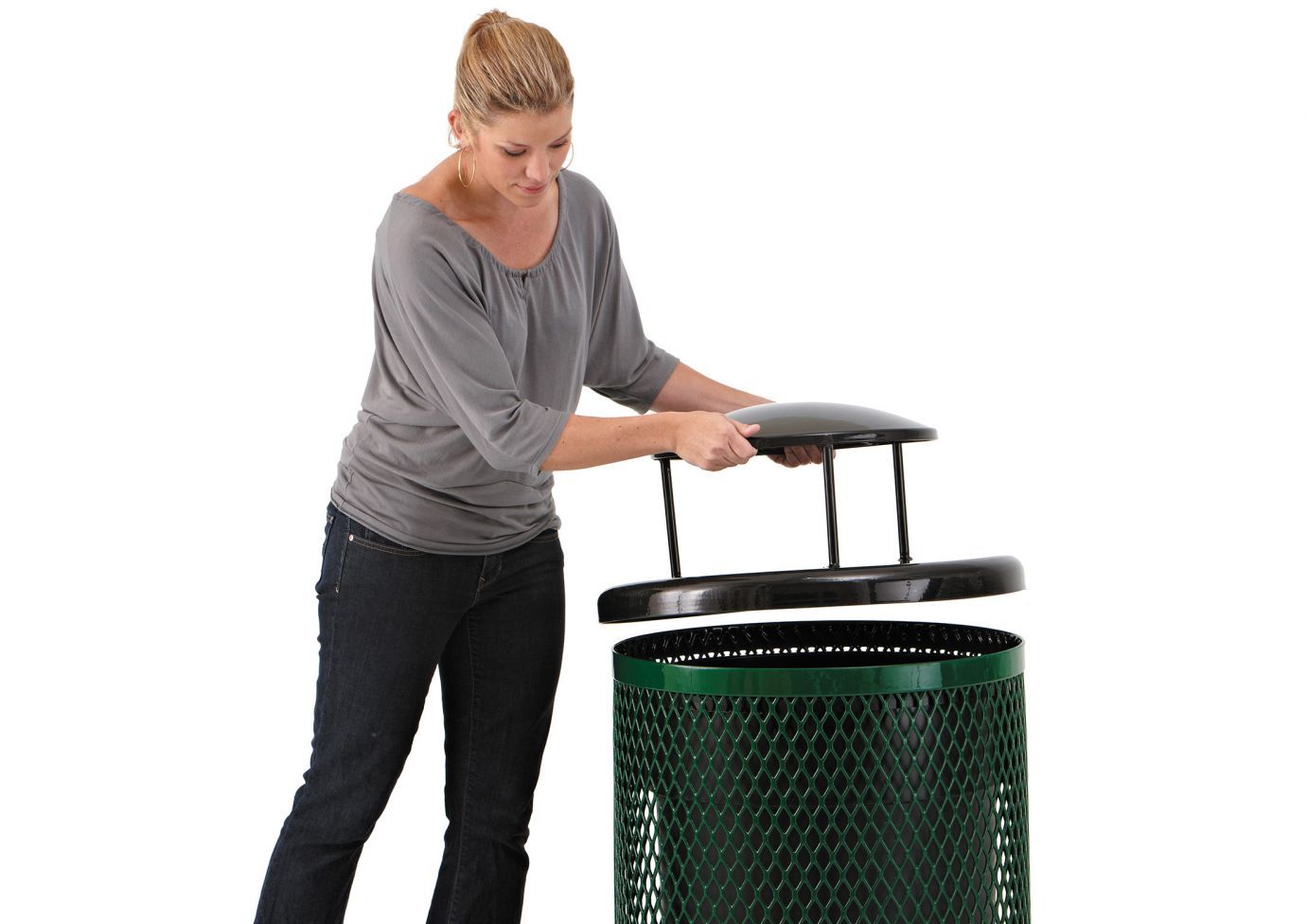 Woman lifting round dome lid off green metal trash receptacle with diamond pattern mesh